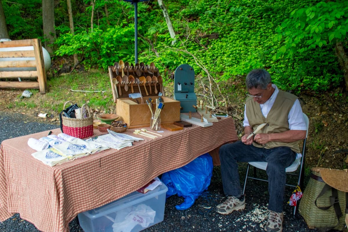 Period craftsman carving wooden spoons